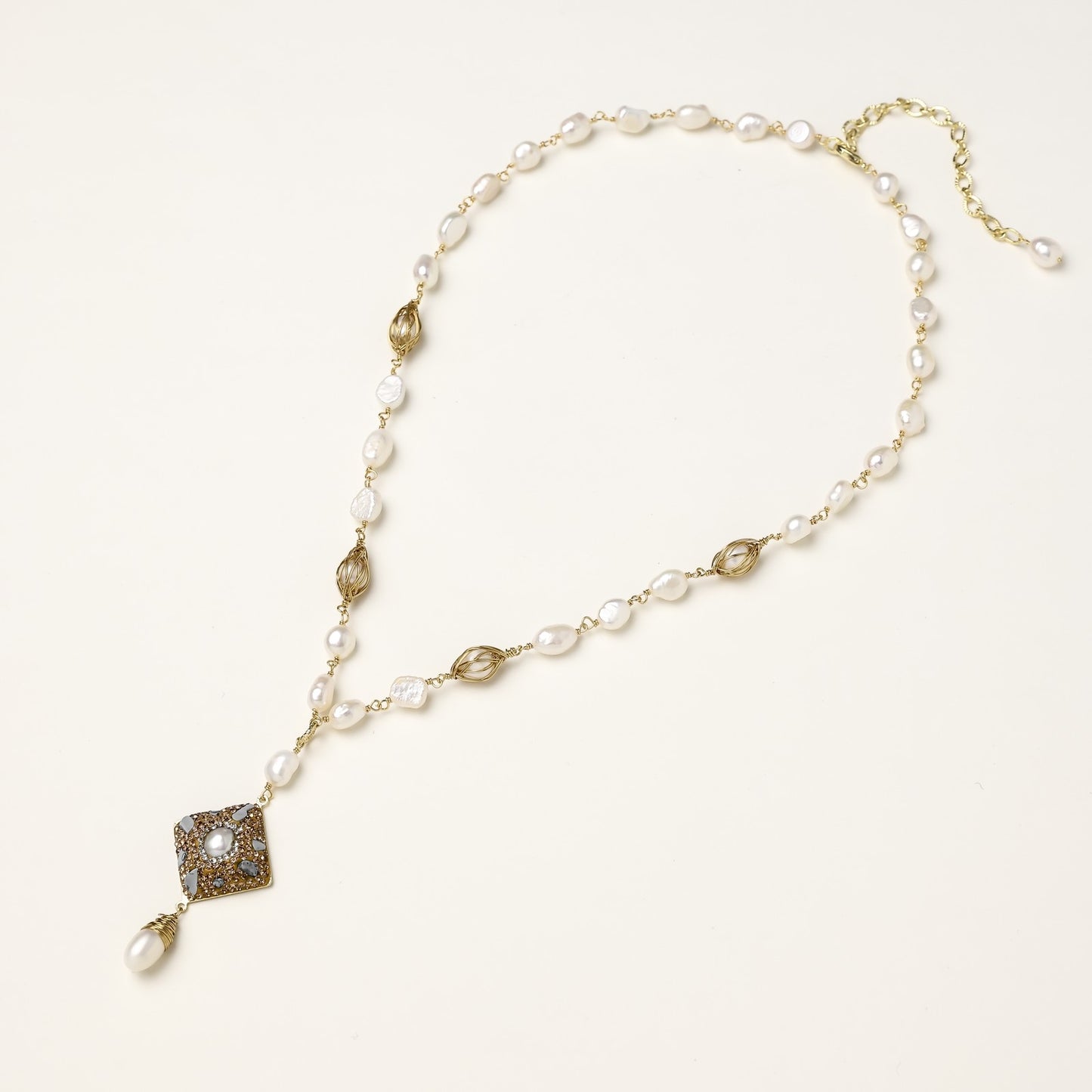 Elegant 14K gold plated necklace with freshwater pearls and ornate crystal diamond pendant on cream background.