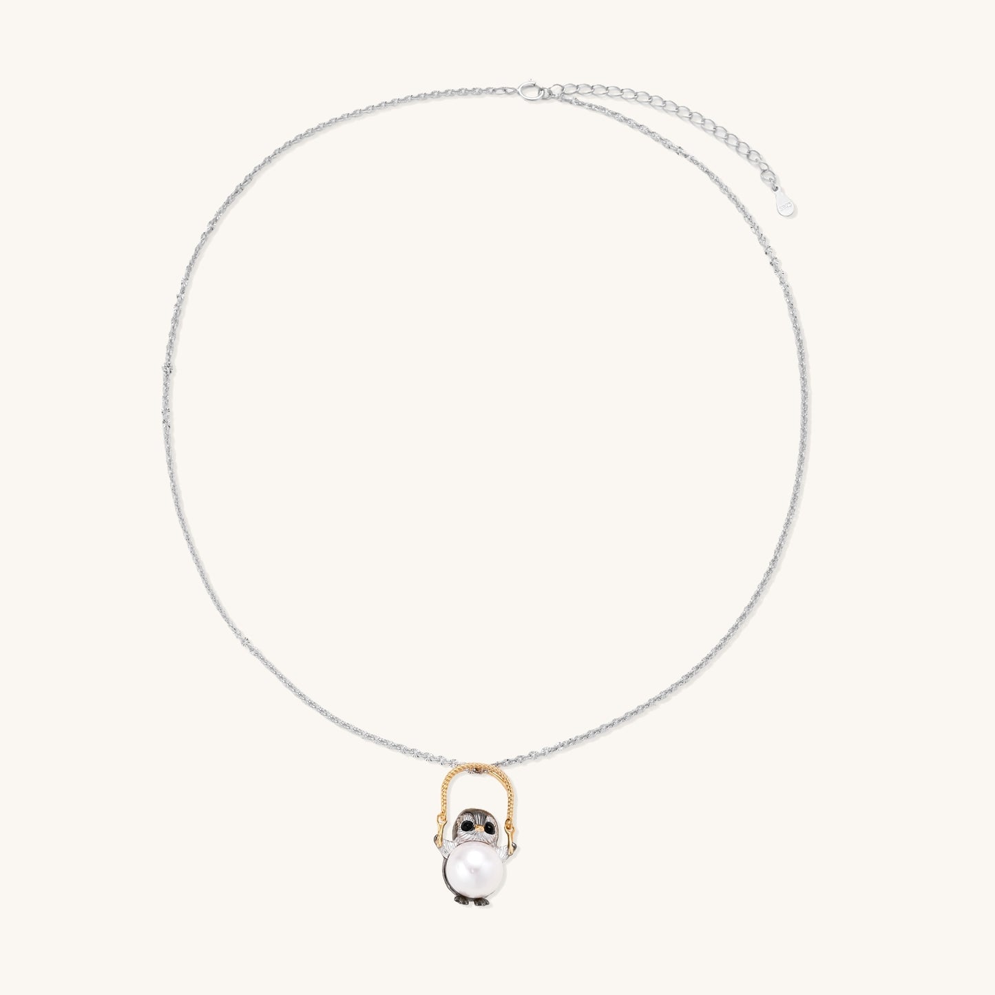 Silver owl pendant holding a round freshwater pearl on an adjustable chain against white background