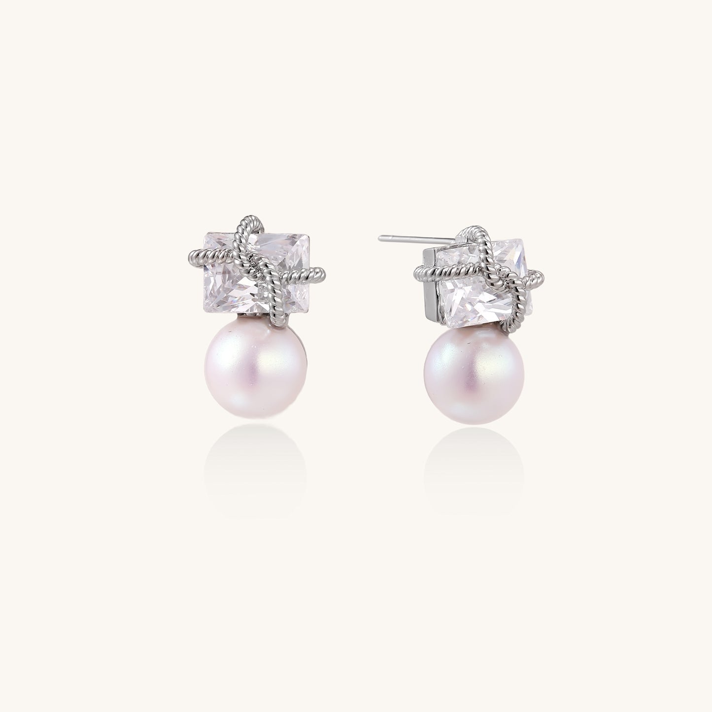 Gold-plated stud earrings with square crystal tops wrapped in twisted wire and freshwater pearl drops on white background