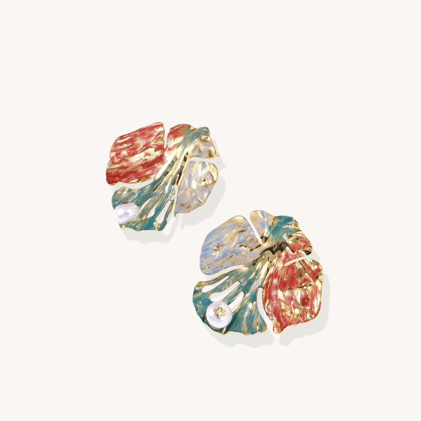 Colorful enamel monstera leaf earrings with pearl accents in teal, coral and gold tones on neutral background.