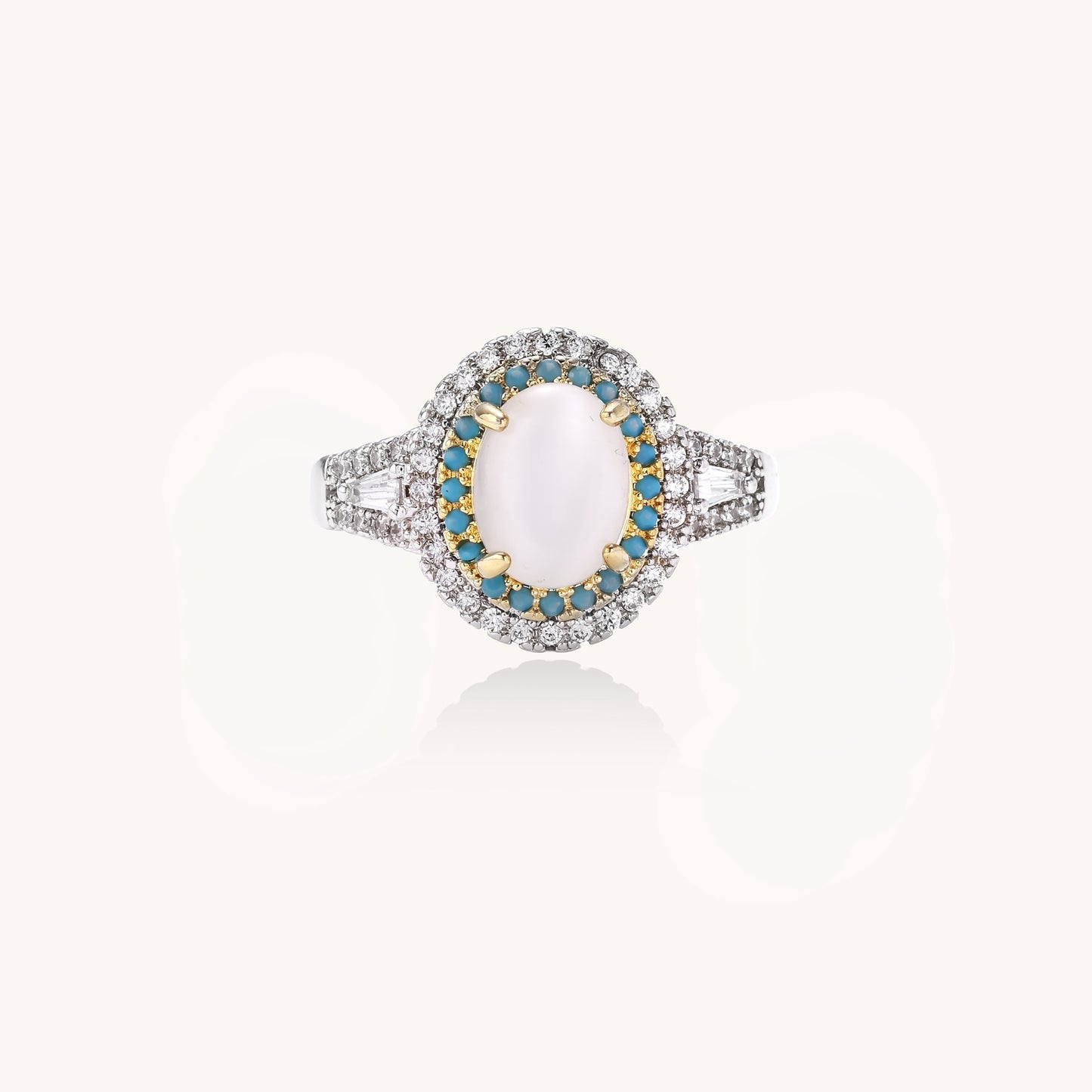 Gold-plated ring with oval cat's eye stone center, blue accent stones, and crystal halo on white background.