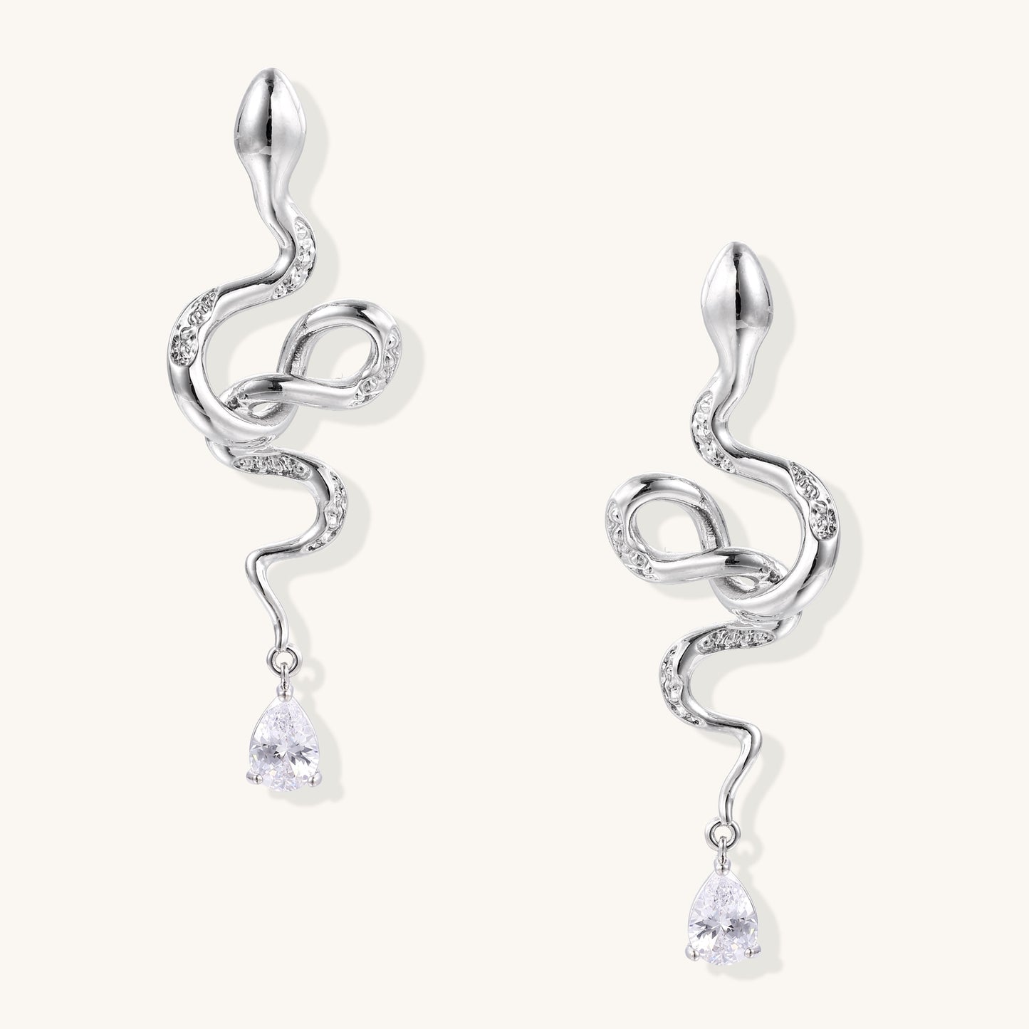 Coiled gold-plated snake earrings with zirconia stones and teardrop crystal dangles against white background.