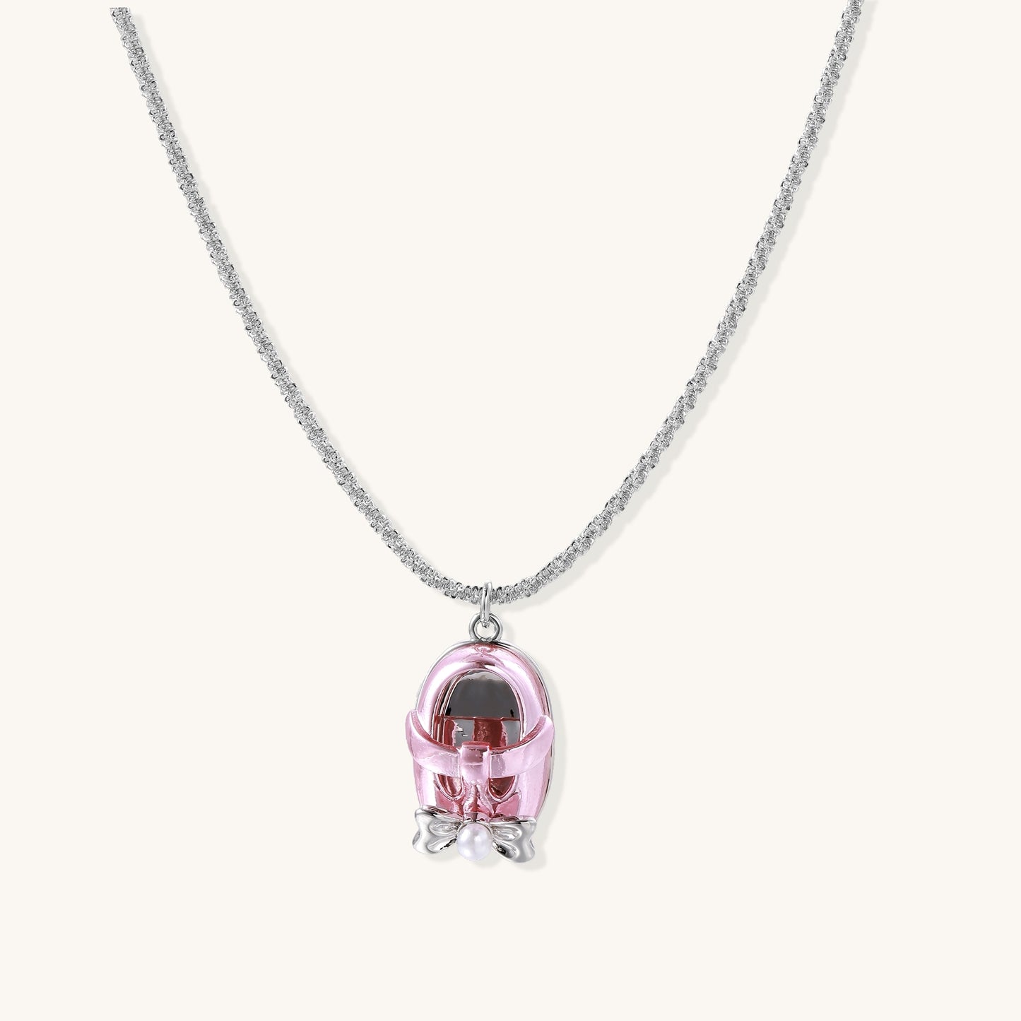 Delicate gold-plated chain necklace with transparent pink-tinted capsule pendant containing decorative bow element
