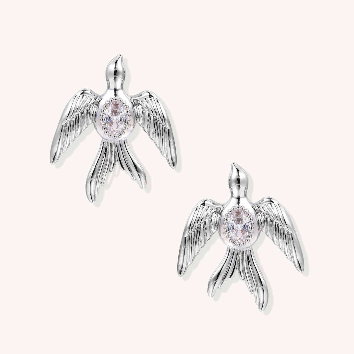 Gold-plated angel wing stud earrings with detailed feather texture and oval zirconia stones in centers
