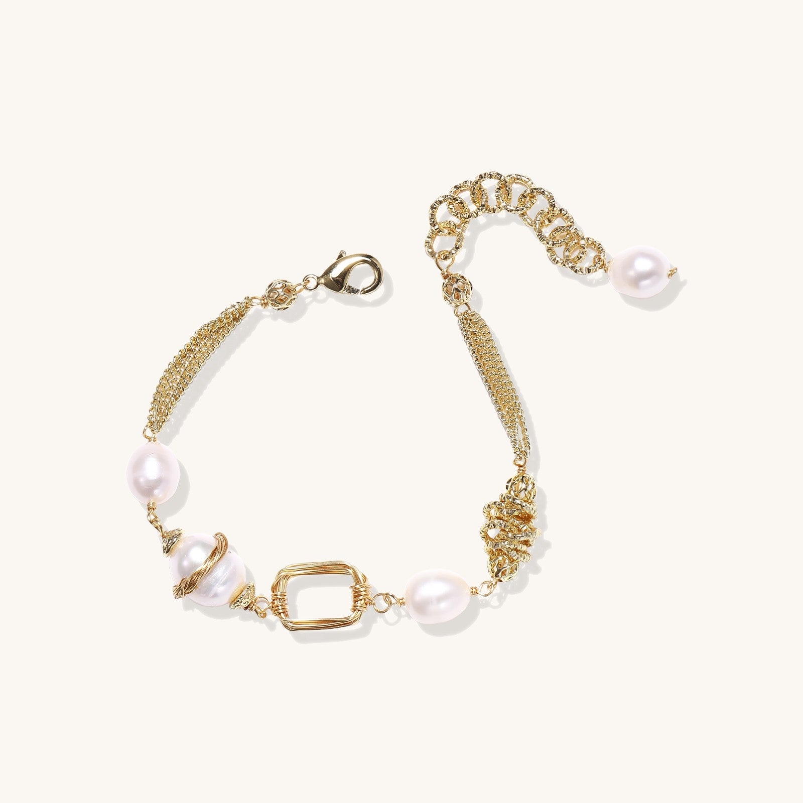 Gold-plated bracelet featuring cream freshwater pearls and decorative chain links on white background.