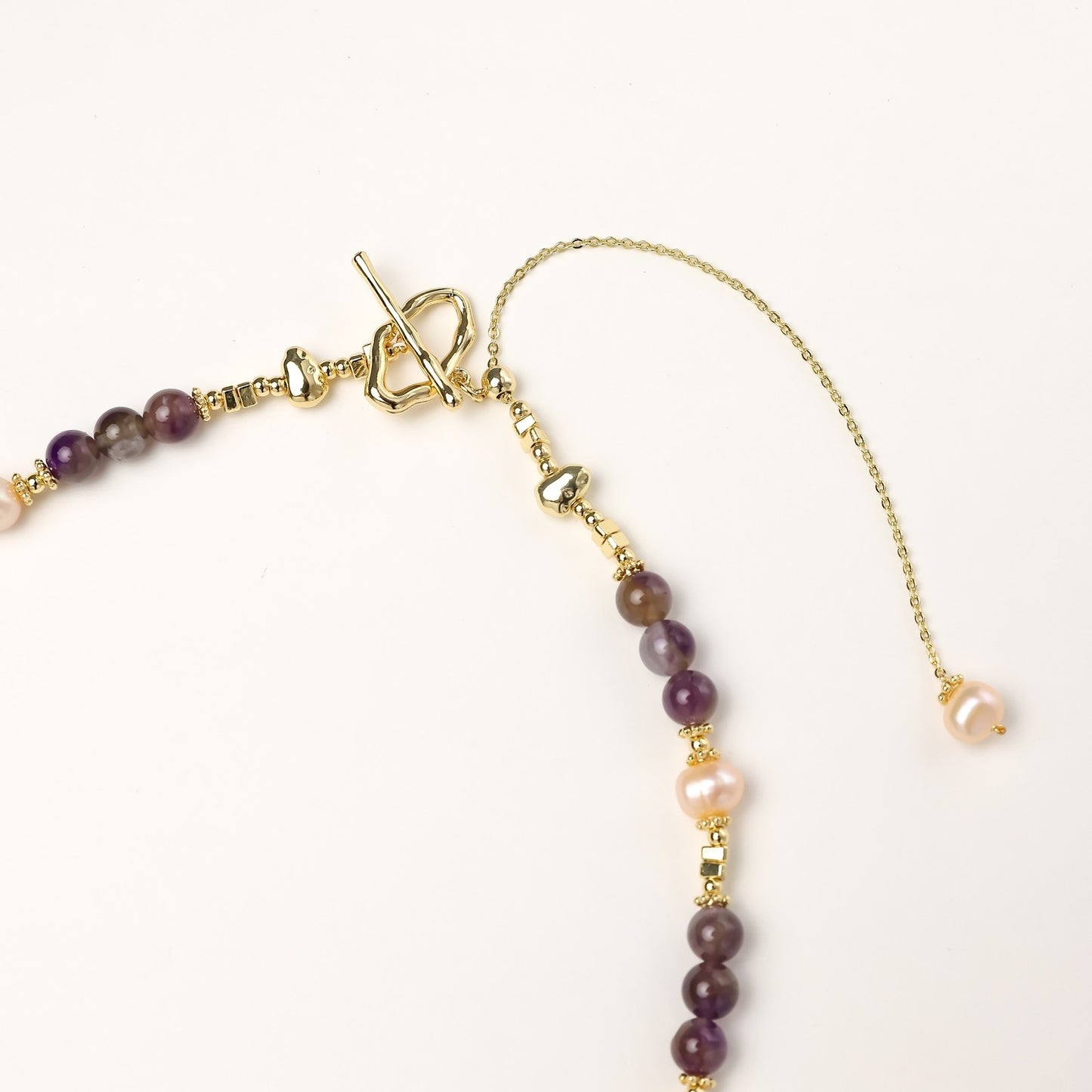 Gold-plated necklace with purple amethyst beads, pink pearls, and iridescent baroque pearl pendant beneath crystal star charm