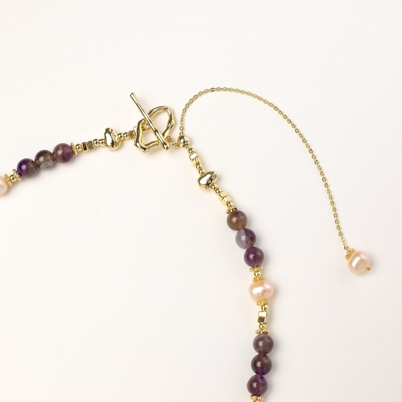 Gold-plated necklace with purple amethyst beads, pink pearls, and iridescent baroque pearl pendant beneath crystal star charm