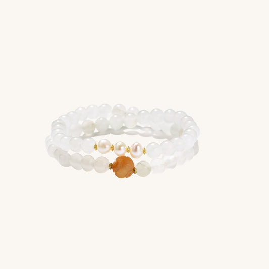 Stretch bracelet with white jade beads, freshwater pearls, and orange agate centerpiece on cream background.