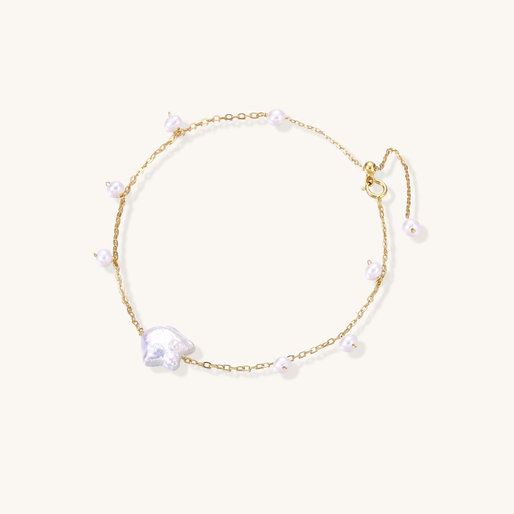 Delicate 18K gold-plated silver chain bracelet with freshwater and baroque pearls on cream background