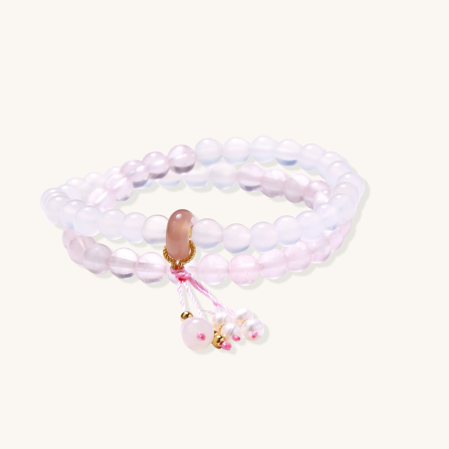 Stretchable bracelet with pink rose quartz and white agate beads, featuring a decorative tassel pendant on white background.