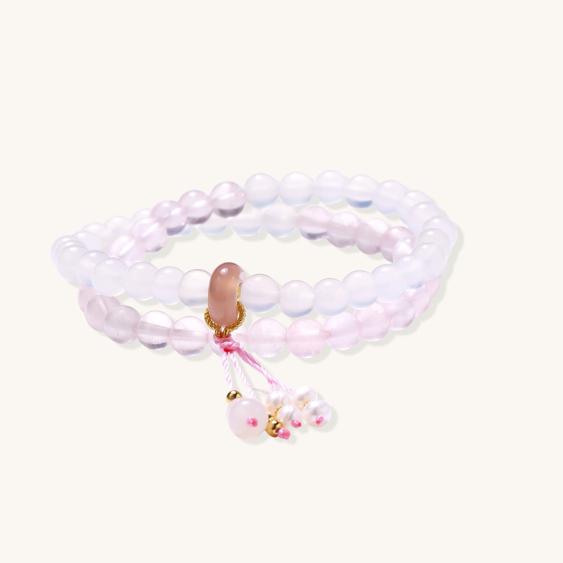 Stretchable bracelet with pink rose quartz and white agate beads, featuring a decorative tassel pendant on white background.