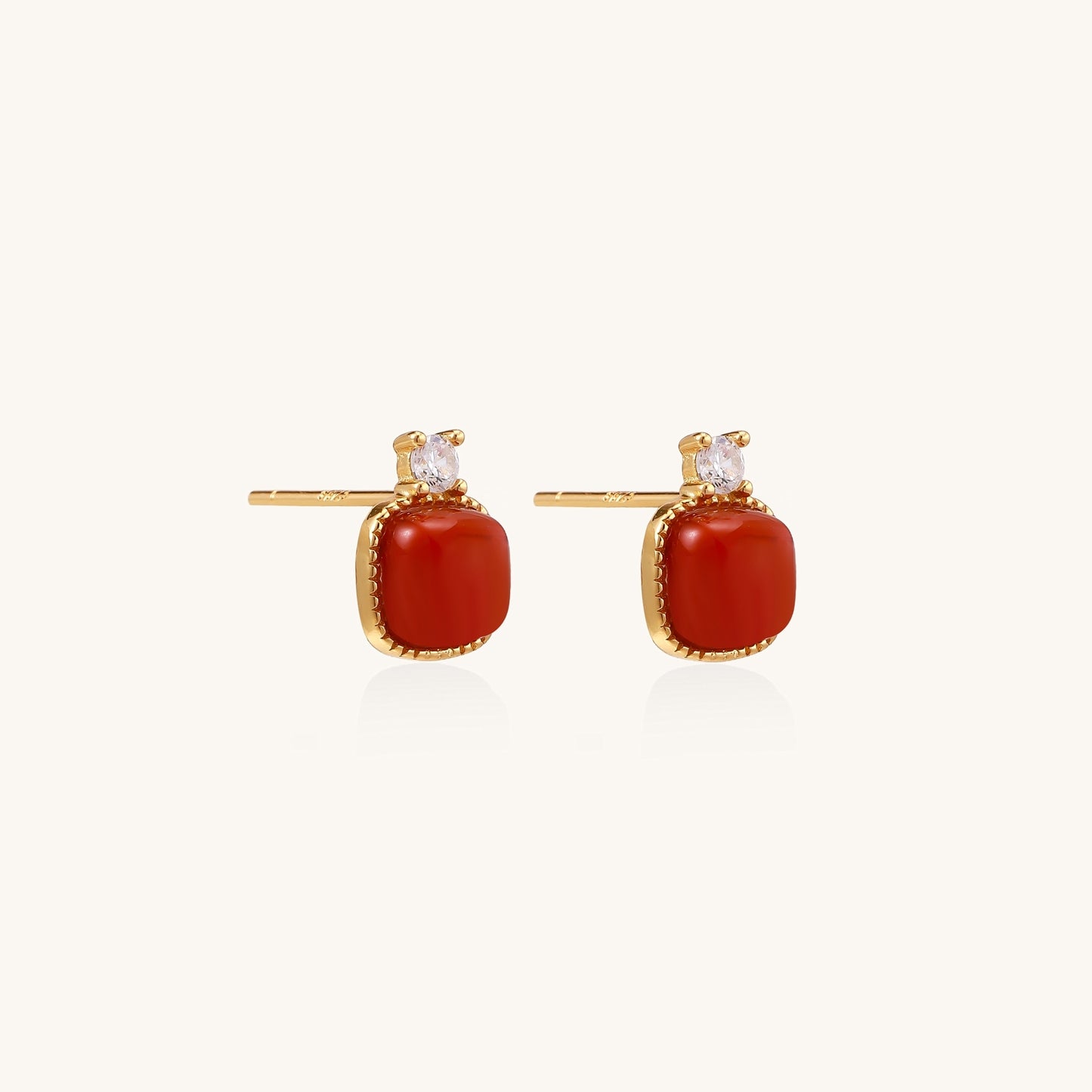 Gold-plated sterling silver stud earrings with square south red agate stones and clear crystals on cream background