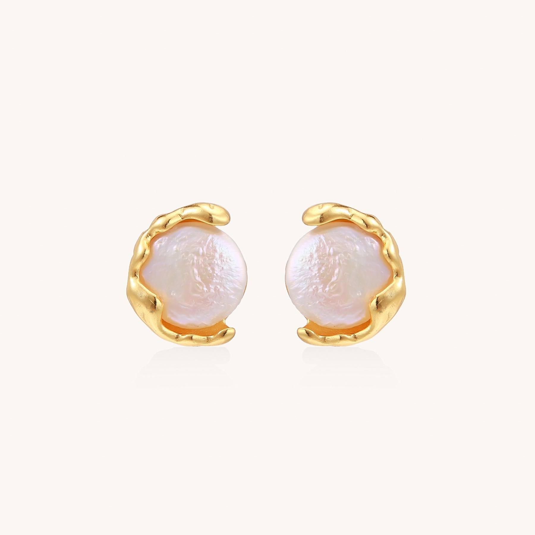 Gold-plated sterling silver stud earrings with organic claw settings cradling lustrous freshwater pearls on white background.