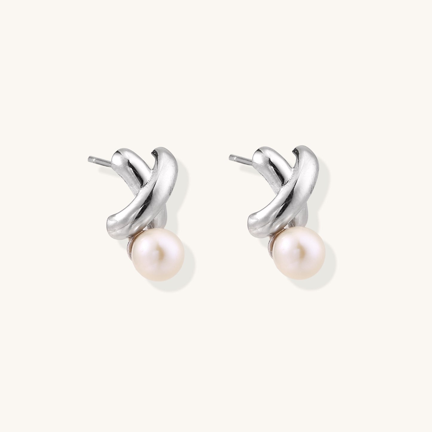 Sterling silver twisted stud earrings with round freshwater pearls on cream background, showing polished finish