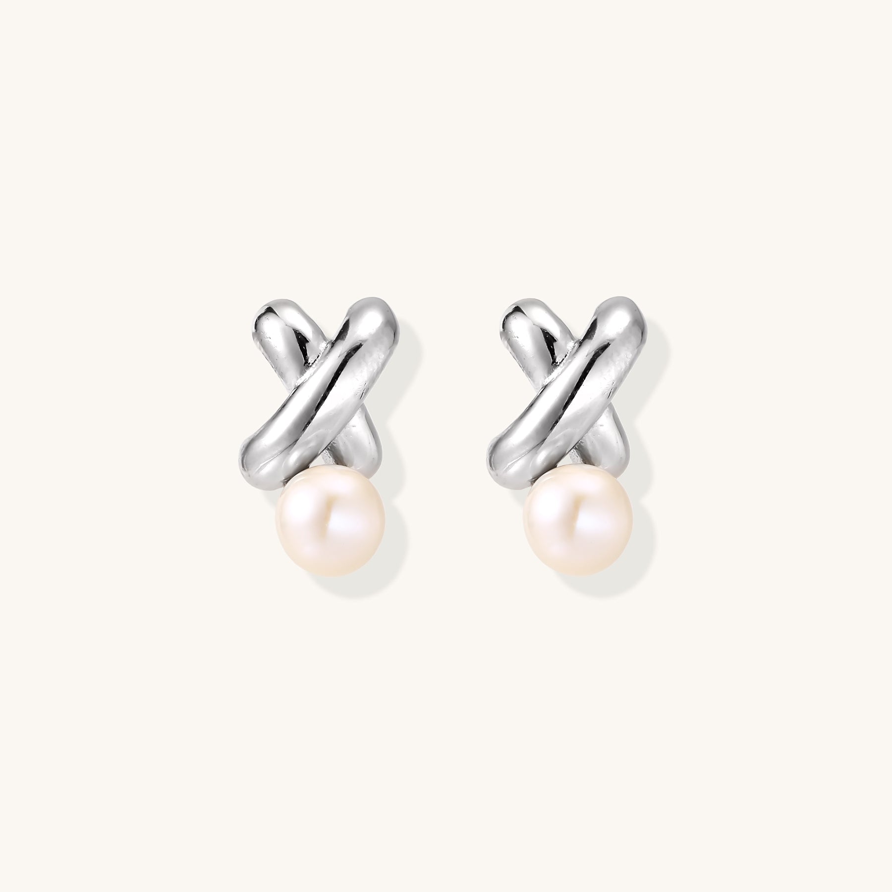 Sterling silver twisted stud earrings with round freshwater pearls on cream background, showing polished finish