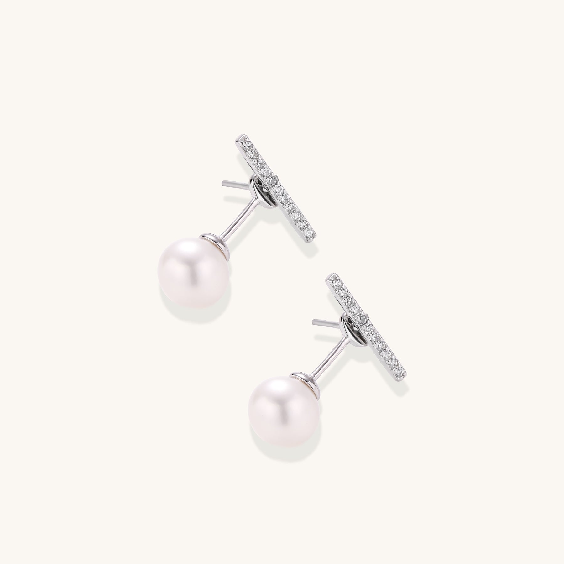 Sterling silver bar stud earrings with freshwater pearl drops on white background, minimalist jewelry design