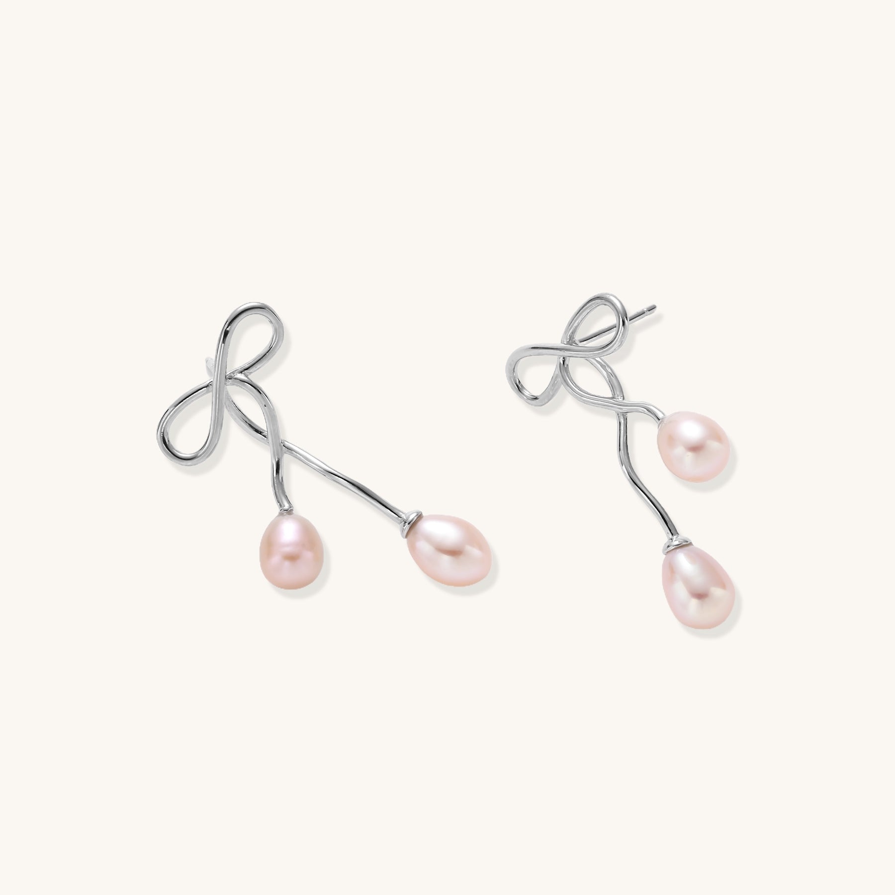 Delicate sterling silver wire earrings with organic bow shapes and two pink freshwater pearls on white background