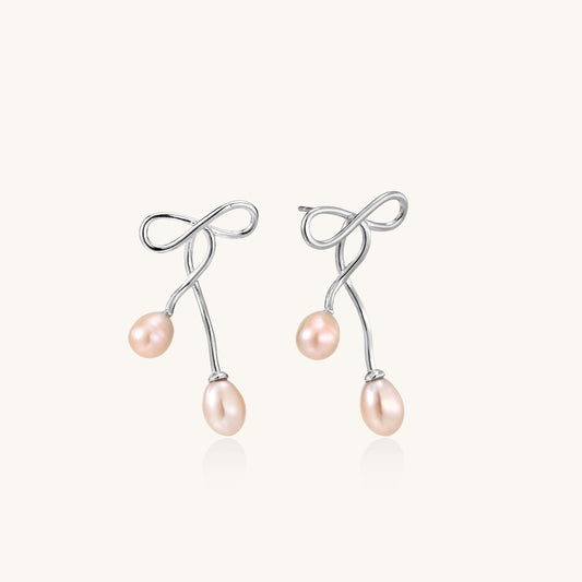 Delicate sterling silver wire earrings with organic bow shapes and two pink freshwater pearls on white background