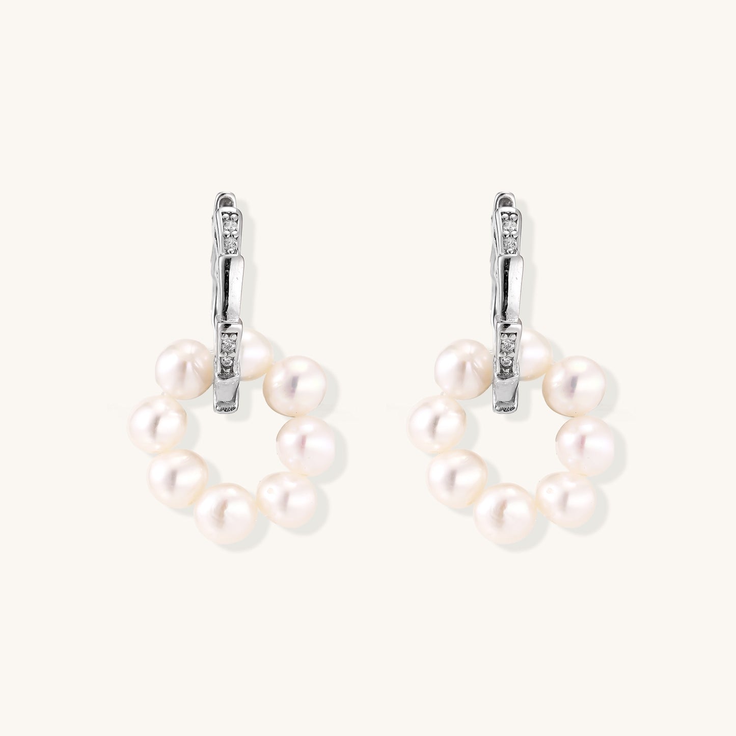 Sterling silver huggie hoop earrings with clustered white freshwater pearls and crystal accents on white background.