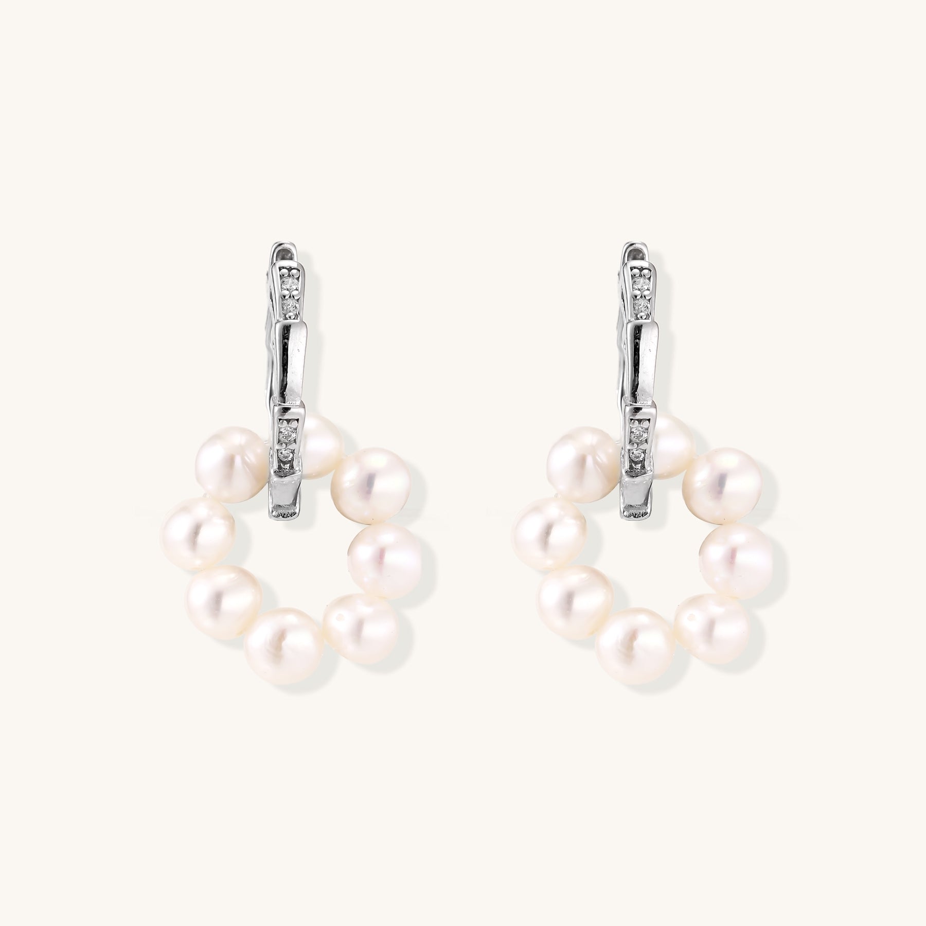 Sterling silver huggie hoop earrings with clustered white freshwater pearls and crystal accents on white background.