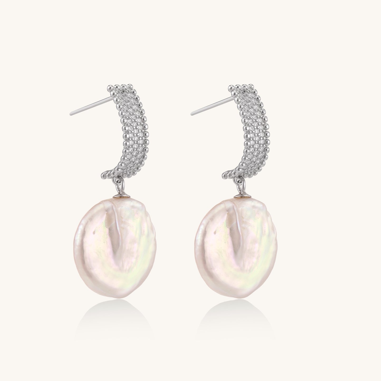 Sterling silver huggie earrings with lustrous baroque pearls displaying iridescent pink and cream tones on white background.