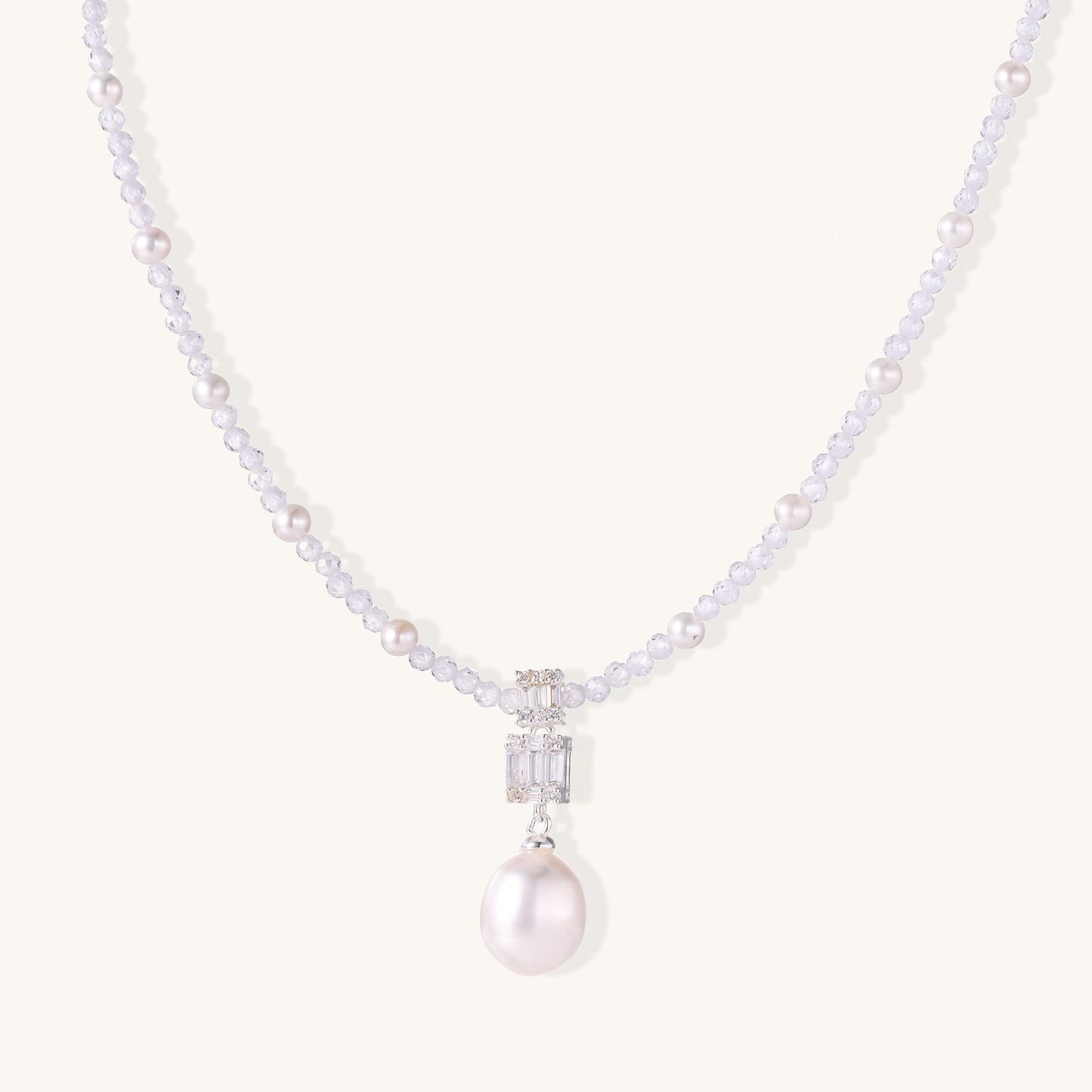 Delicate beaded necklace with lavender crystals, white pearls, and crystal pendant with pearl drop on white background.