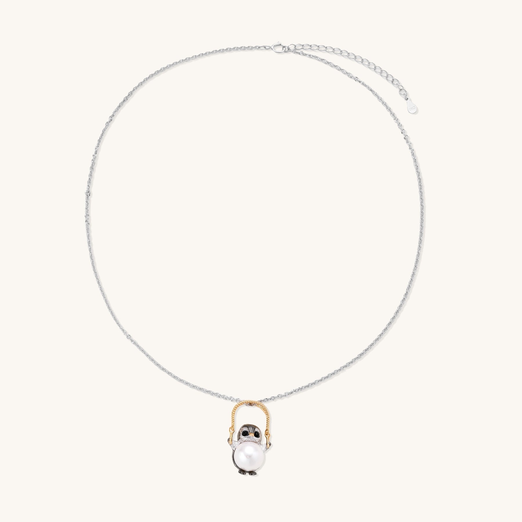 Silver owl pendant holding a round freshwater pearl on an adjustable chain against white background