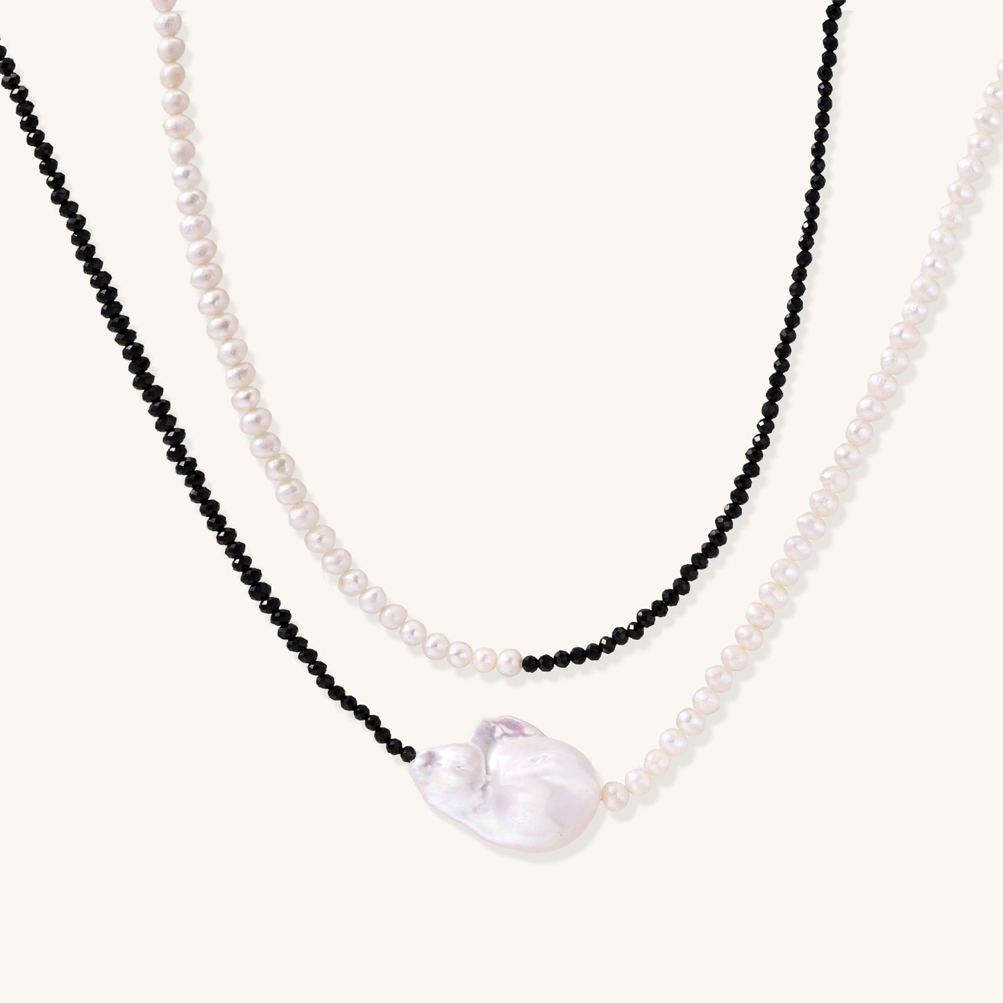 Two-strand necklace with black crystal beads and white pearls featuring a large baroque pearl centerpiece on white background.