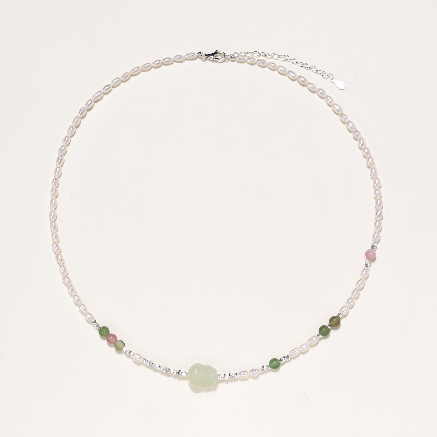 Delicate sterling silver necklace with freshwater pearls, green serpentine centerpiece, and mixed agate beads on white background.