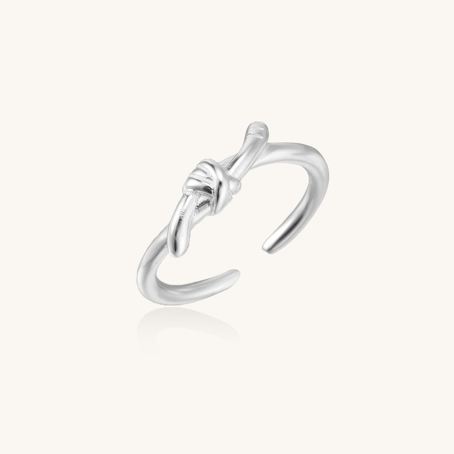 Delicate sterling silver ring with geometric knot design on white background, showcasing adjustable open band.