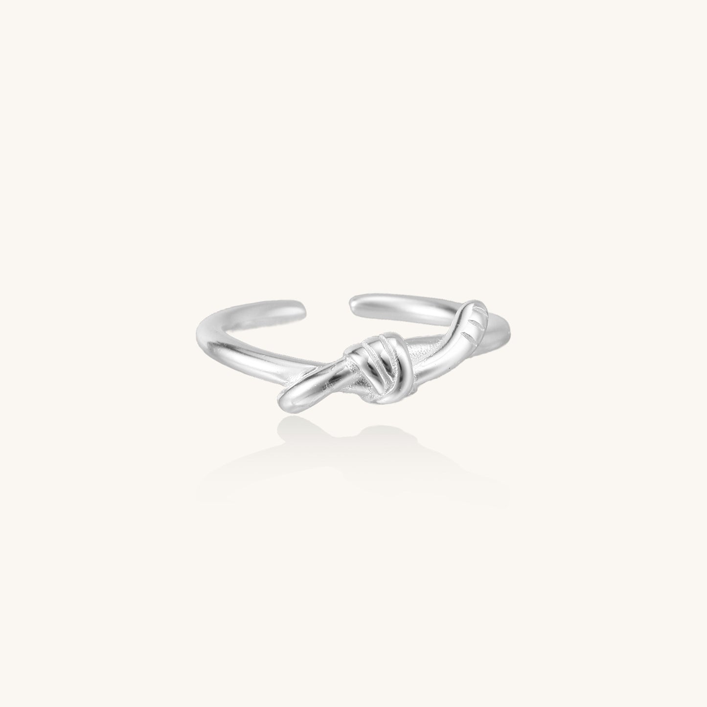 Delicate sterling silver ring with geometric knot design on white background, showcasing adjustable open band.