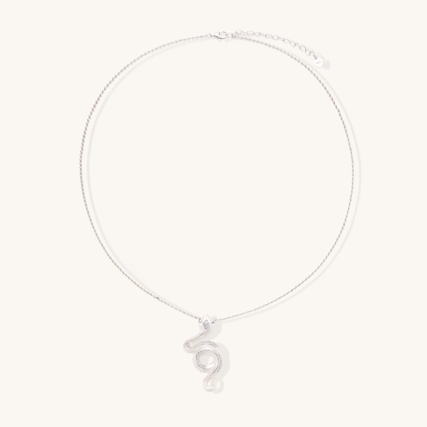 Sterling silver snake pendant necklace with zirconia crystals on adjustable chain against cream background