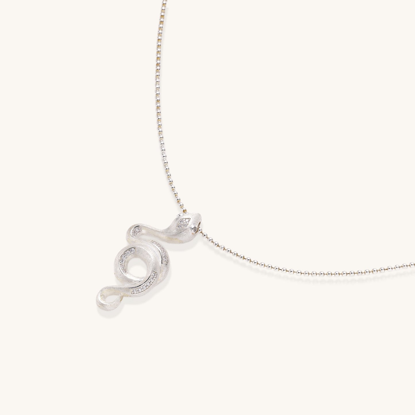 Sterling silver snake pendant necklace with zirconia crystals on adjustable chain against cream background