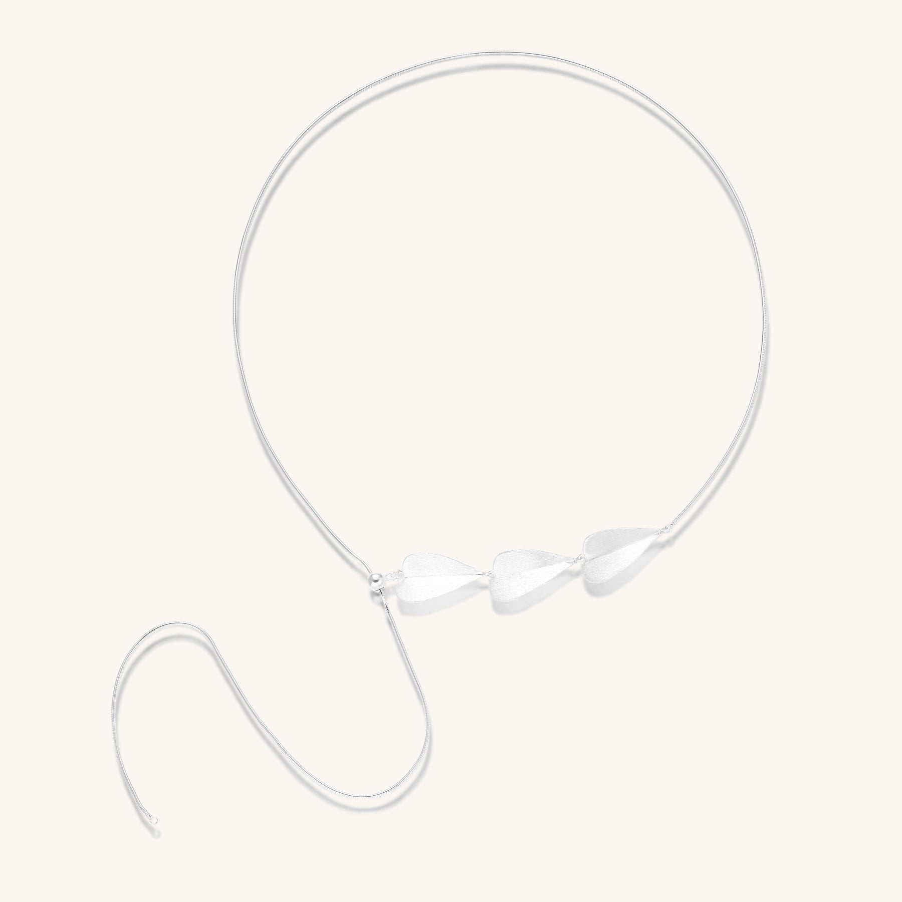 Delicate sterling silver necklace with brushed leaf pendants distributed along a fine chain on white background.