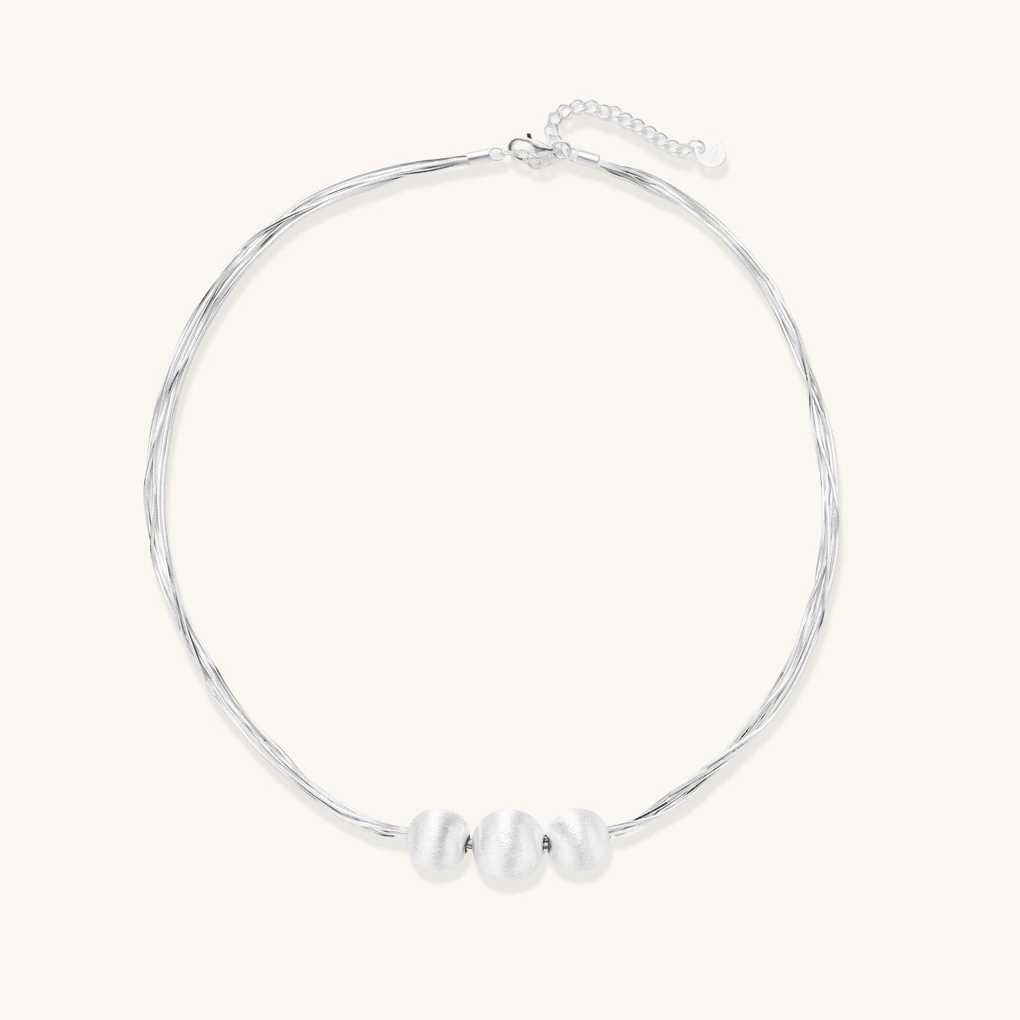 Multi-strand sterling silver necklace with three polished round beads clustered at center on white background.