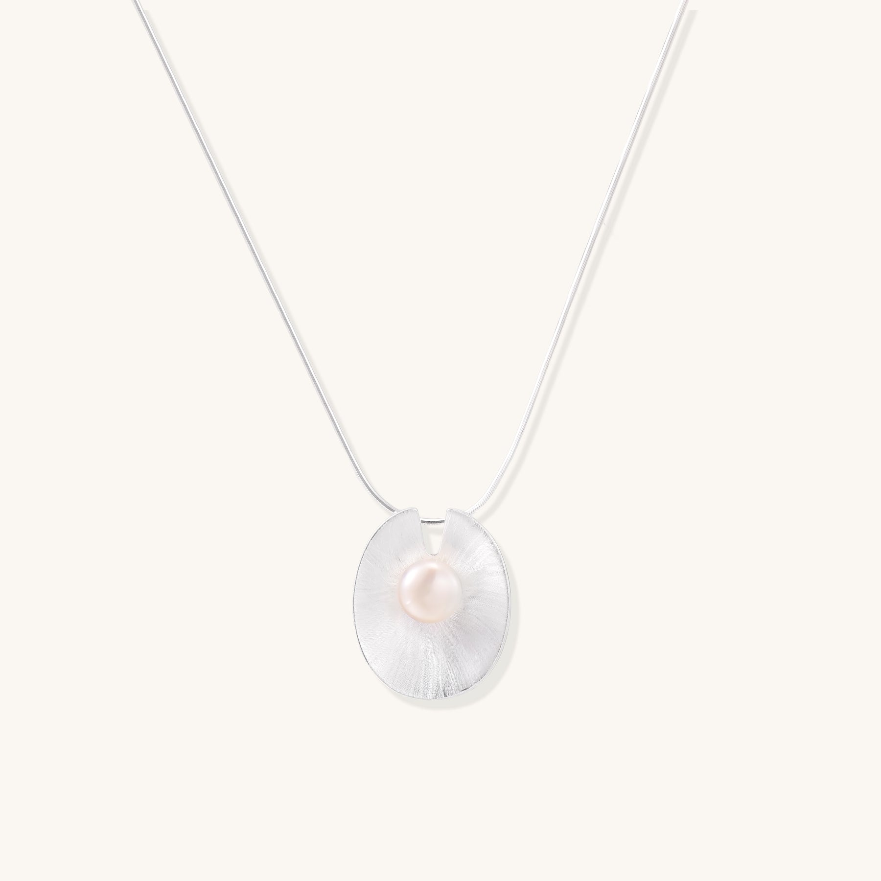 Delicate sterling silver necklace with oval iridescent pendant and central freshwater pearl on white background