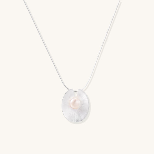 Delicate sterling silver necklace with oval iridescent pendant and central freshwater pearl on white background