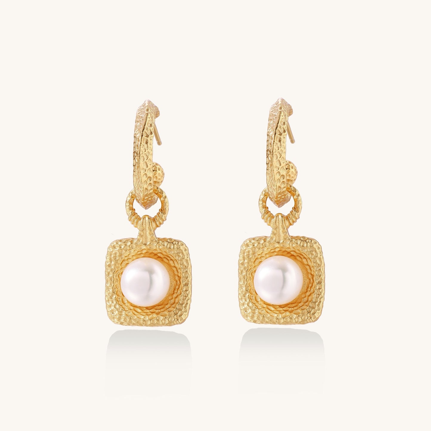 Gold-plated textured hoop earrings with square pendants containing freshwater pearls on white background