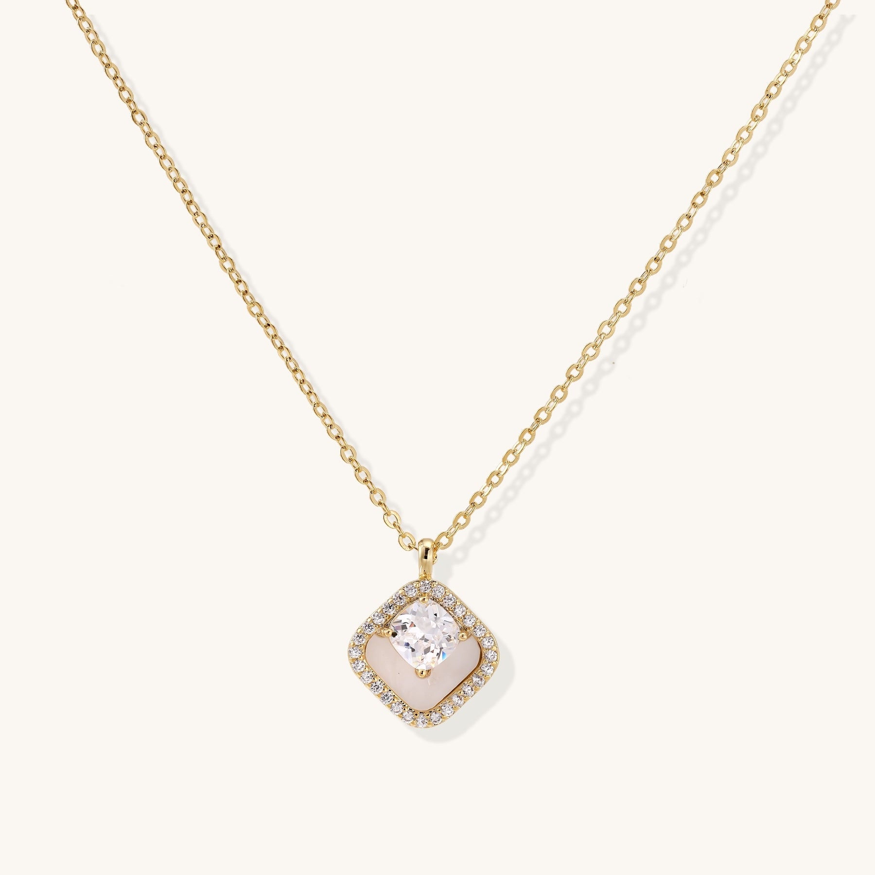 Gold-plated necklace with cushion-shaped pendant featuring a freshwater pearl surrounded by crystal halo on white background.