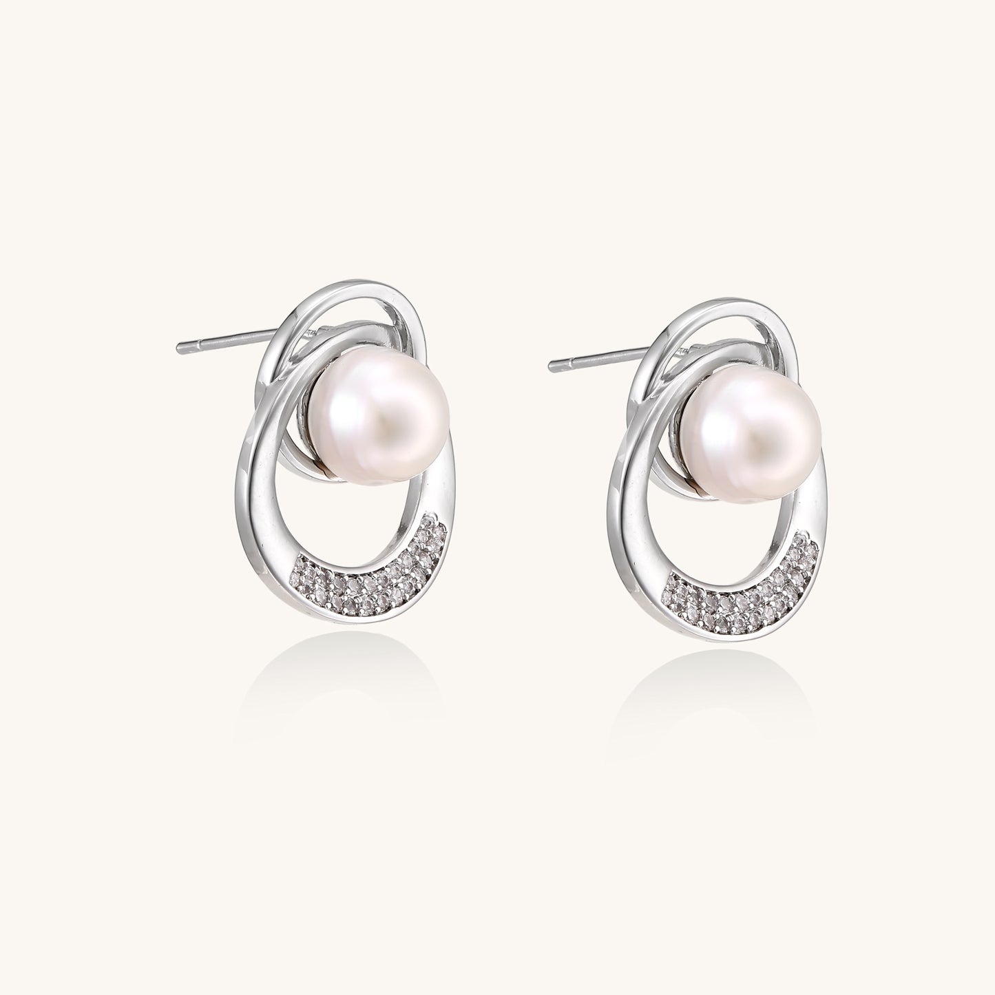 Gold-plated brass stud earrings with swirled circular design holding white freshwater pearls and small crystals