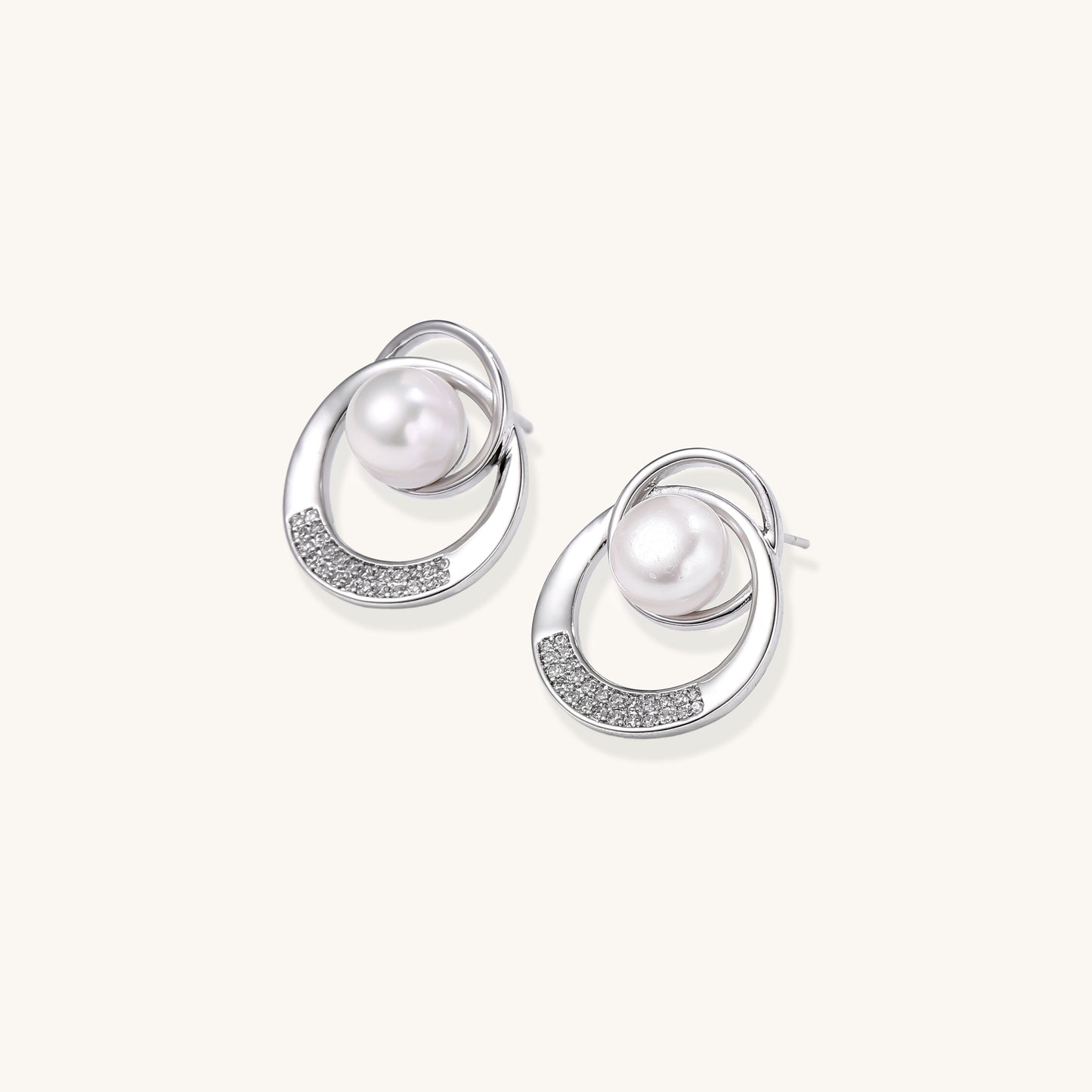 Gold-plated brass stud earrings with swirled circular design holding white freshwater pearls and small crystals