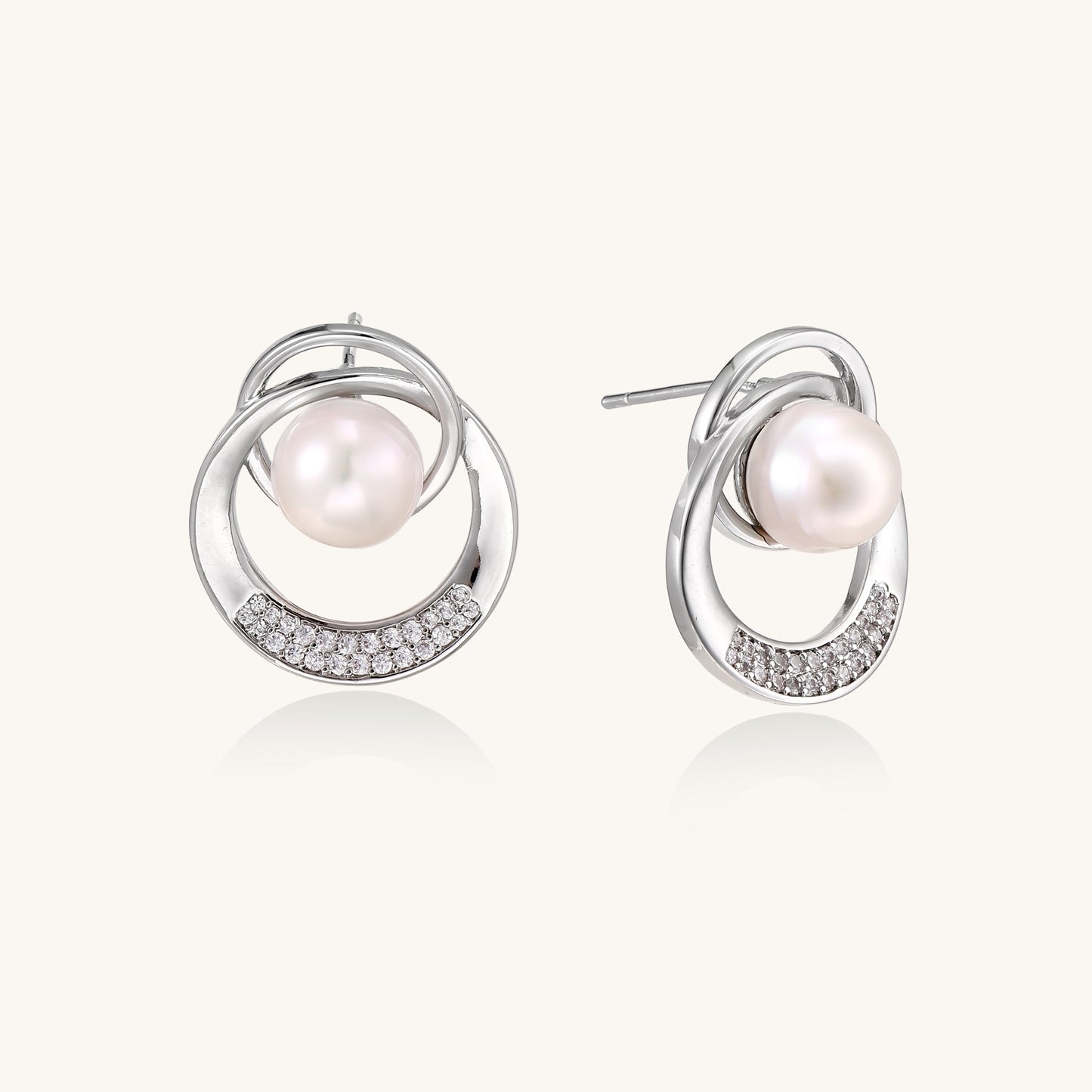 Gold-plated brass stud earrings with swirled circular design holding white freshwater pearls and small crystals