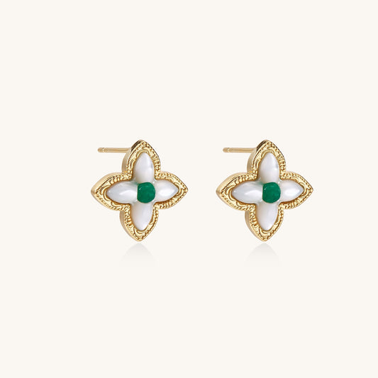 Dainty gold-plated quatrefoil stud earrings with white mother-of-pearl petals and green gemstone centers on beige background.