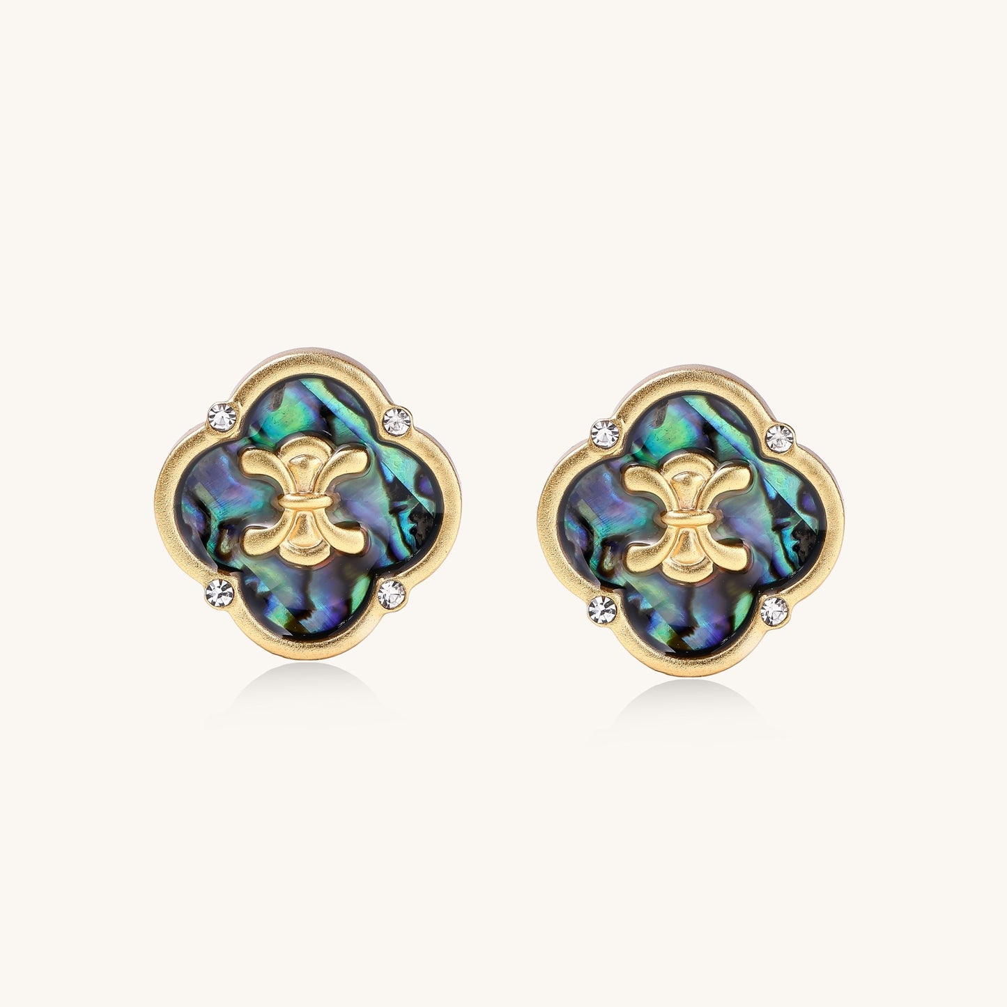 Gold-plated quatrefoil stud earrings featuring iridescent abalone shell centers with decorative motifs and crystal accents