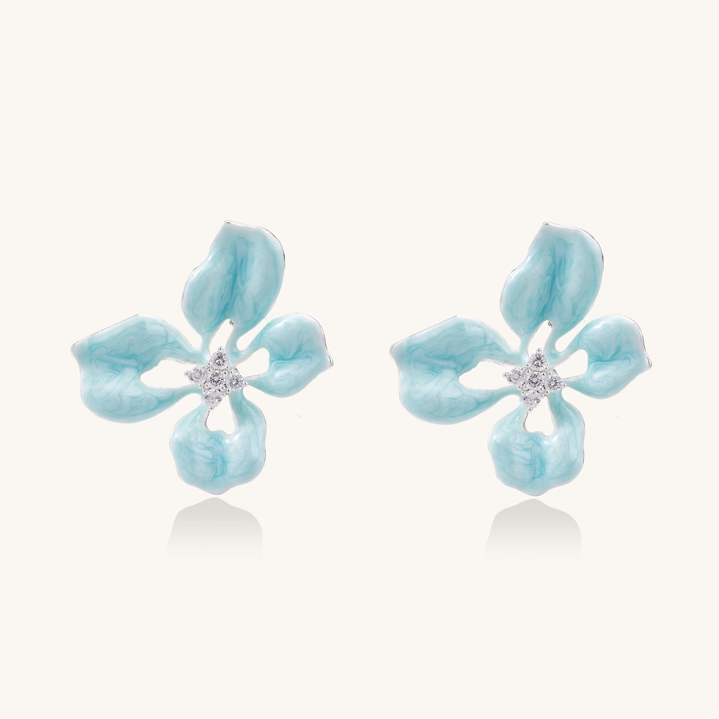 Turquoise blue enamel flower earrings with crystal centers and gold-plated brass posts on white background.