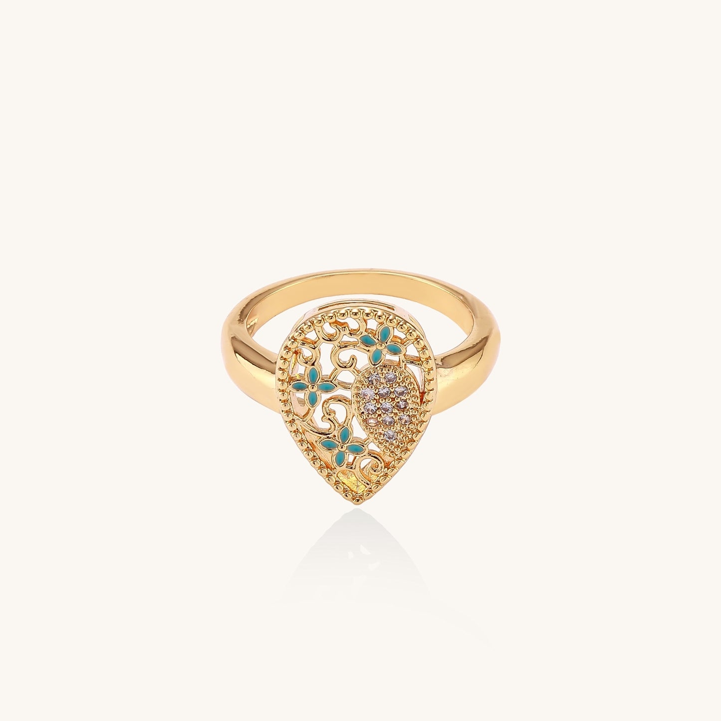 Gold-plated heart ring with turquoise enamel scrollwork and cubic zirconia stones on white background