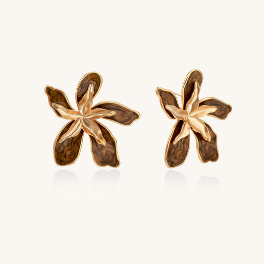 Large gold-plated flower earrings with brown enamel marbled petals on beige background, showing intricate floral design.
