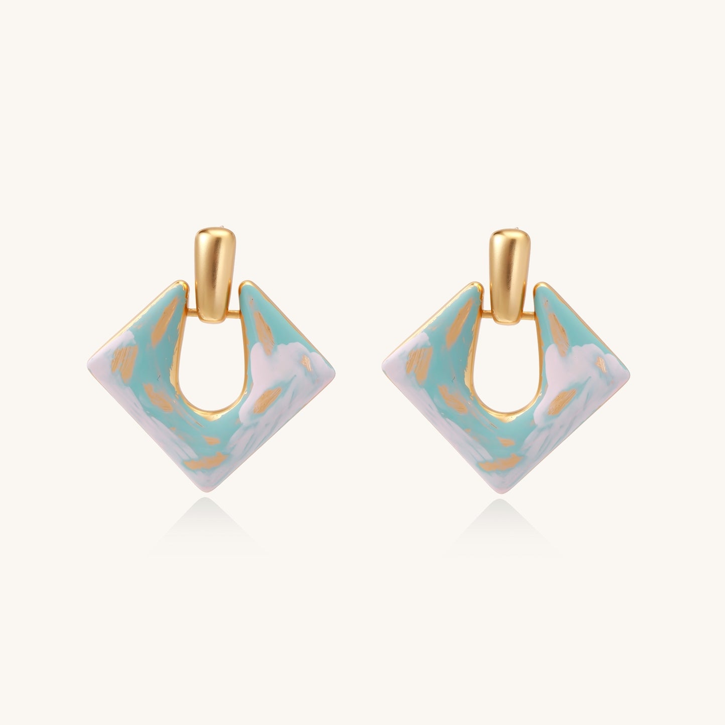 Diamond-shaped gold-plated earrings with pastel marble enamel in turquoise and lavender swirls on beige background