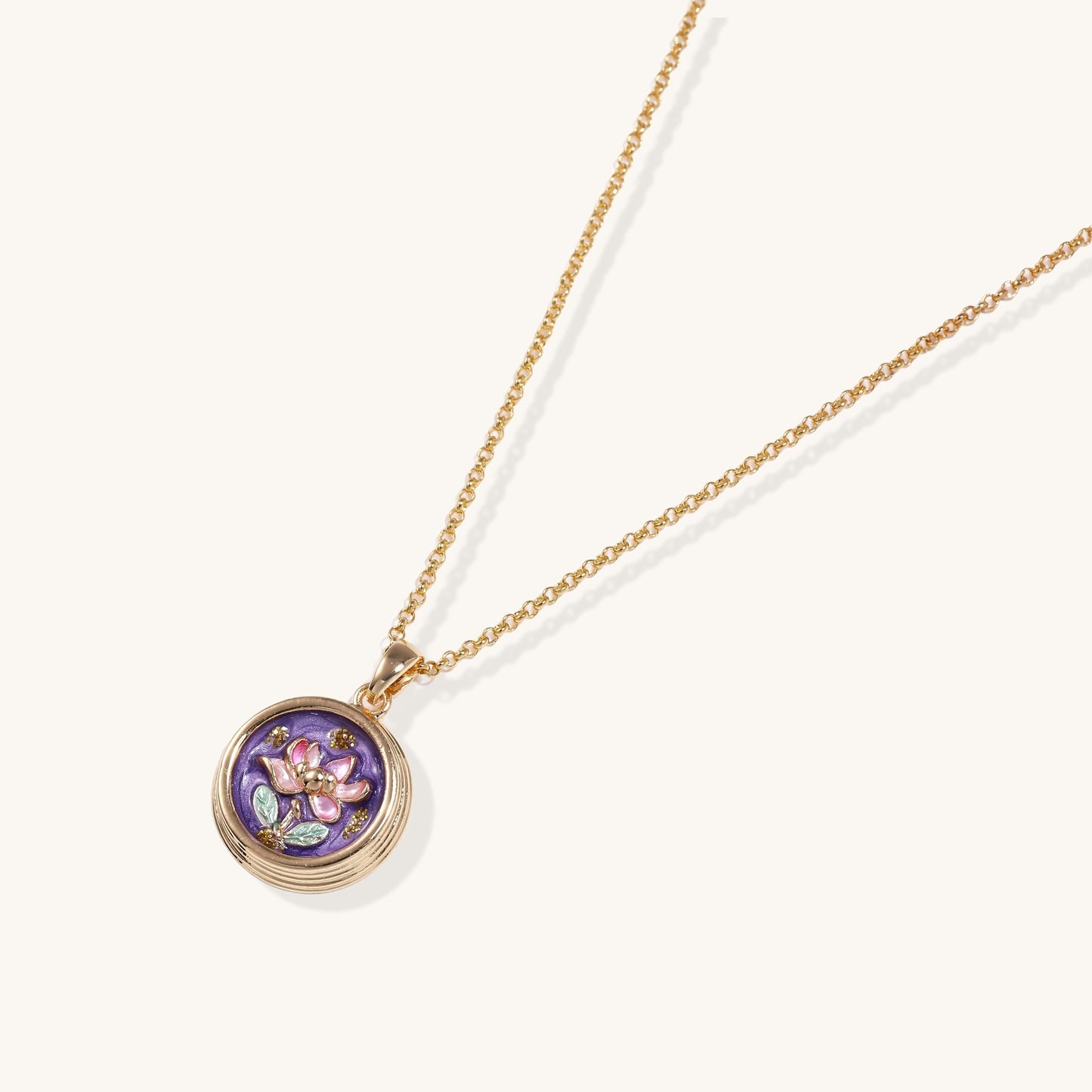 Gold-plated necklace with purple enamel pendant featuring pink floral design on white background