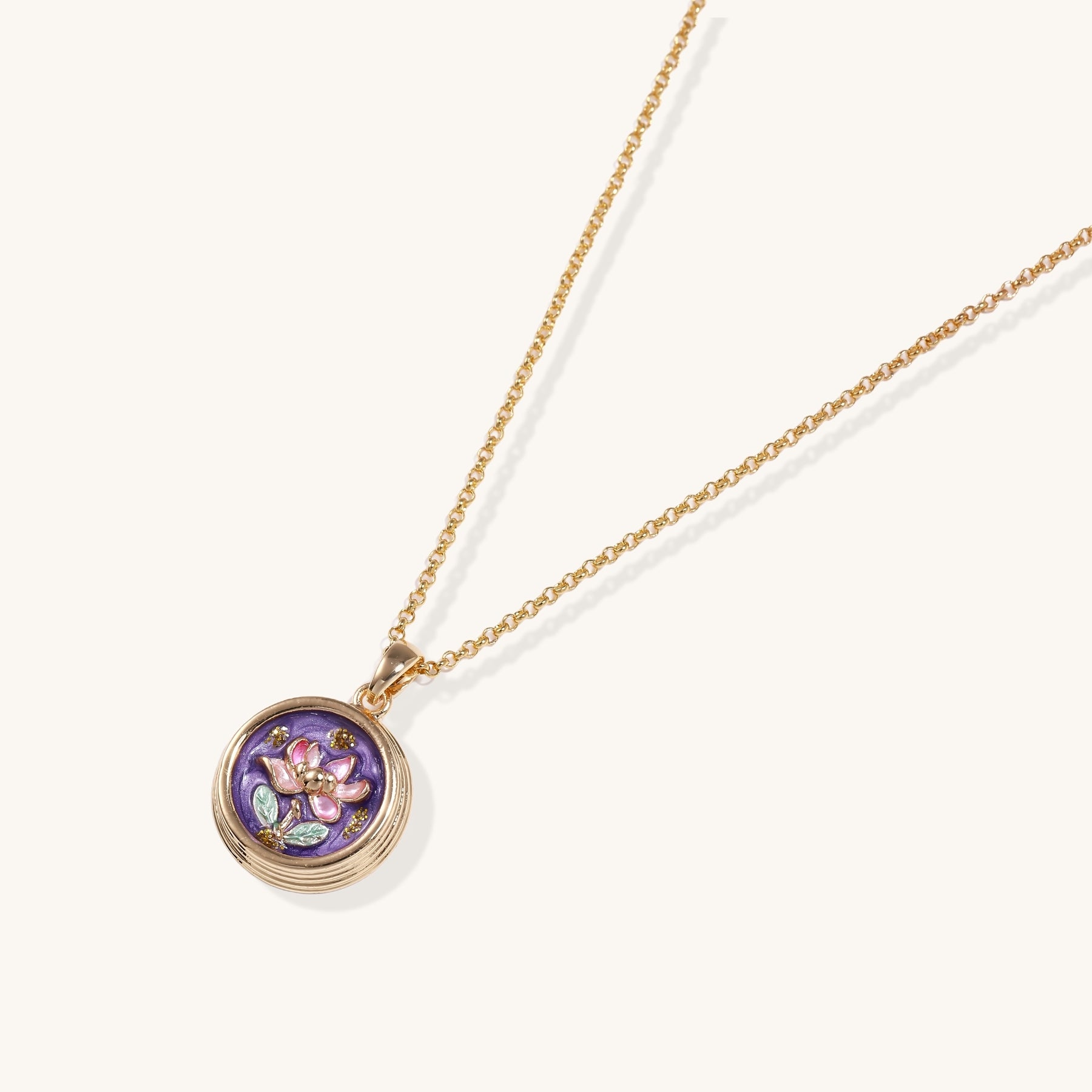 Gold-plated necklace with purple enamel pendant featuring pink floral design on white background